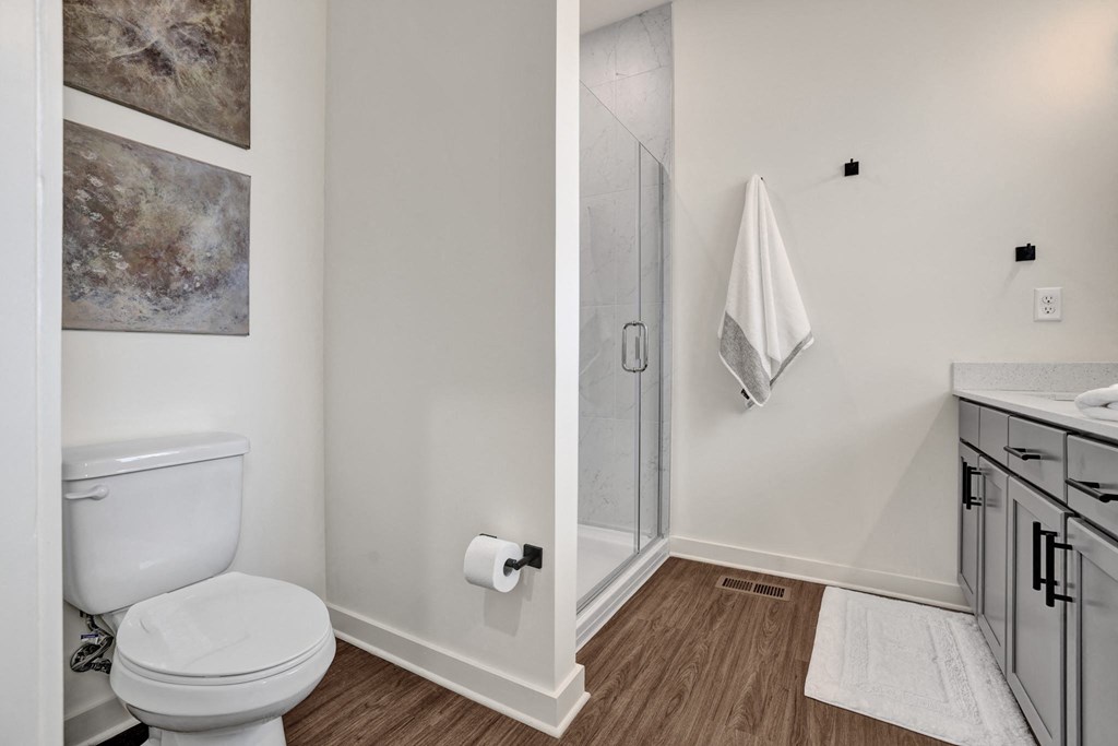 Modern bathroom with double vanity, stand up shower and plank flooring at West Row Lofts and Townhomes in Birmingham, AL